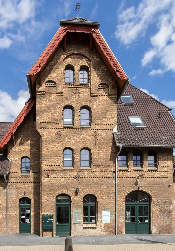 Ein historisches Bahnhofsgebäude in Rheinbach, NRW, Deutschland mit grünen Türen und Fensterrahmen an einem sonnigen Tag mit blauem Himmel und ein paar Wolken. In diesem Gebäude befindet sich das „Come in“. 